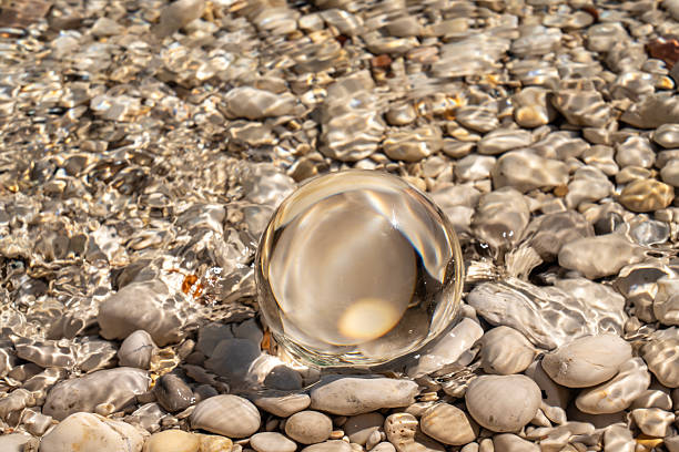One crystal ball lying on the beach Sakarun, mirroring pebbles on ground. Dugi otok island, Croatia