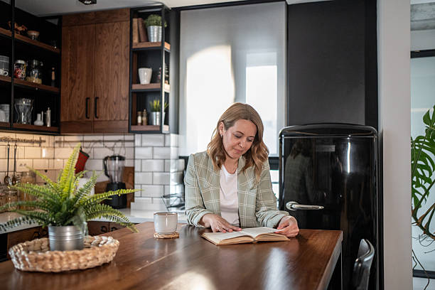 istock Woman enjoying a book and coffee in her modern kitchen 2209401813