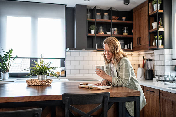 istock Woman enjoying a book and coffee in her modern kitchen 2209401859