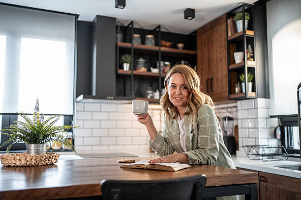 istock Woman enjoying coffee and book in modern kitchen 2209401874
