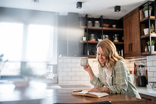 istock Woman enjoying coffee and book in modern kitchen 2209401882