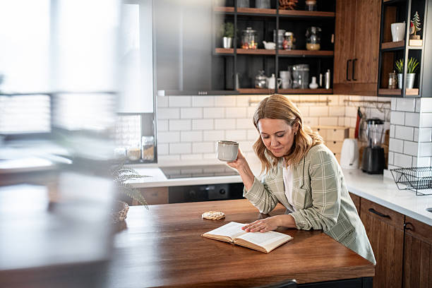 istock Woman enjoying coffee and book in modern kitchen 2209401898