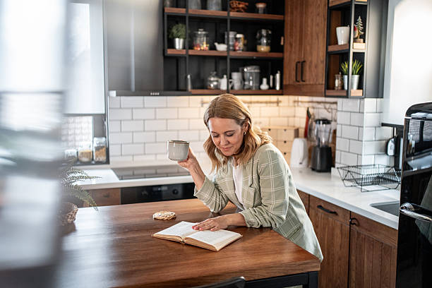 Woman enjoying coffee and book in modern kitchen