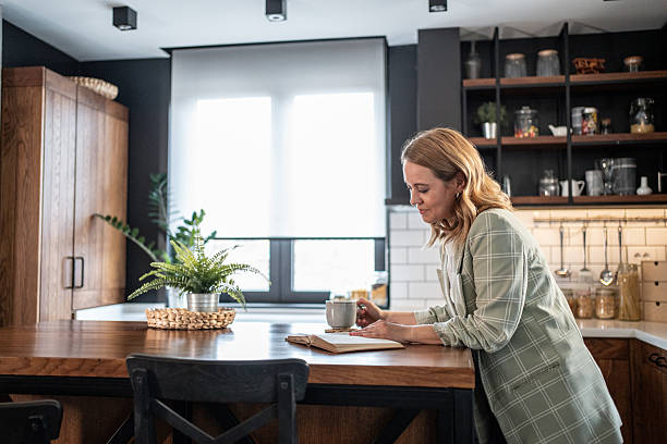 istock Woman enjoying a book and coffee in her modern kitchen 2209401907