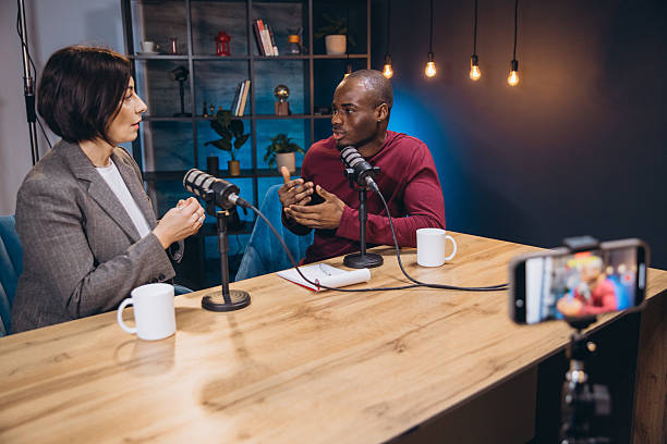 istock Two diverse podcasters are recording a podcast in a professional studio, engaging in a conversation 2209402676
