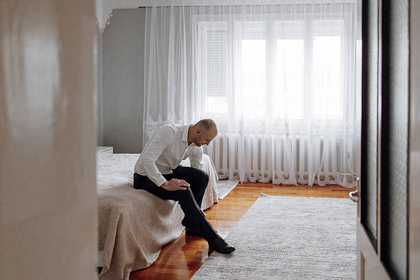 istock A man is sitting on a bed in a room with a window 2209402852