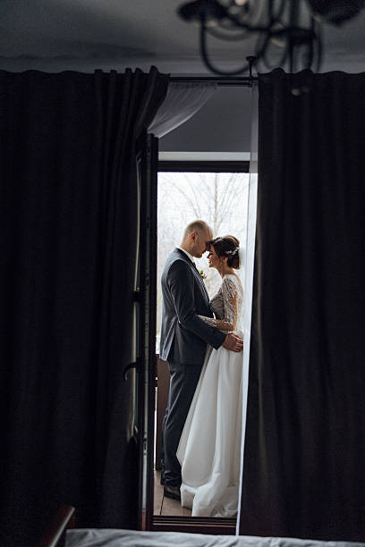 istock A bride and groom are standing in front of a window 2209402962