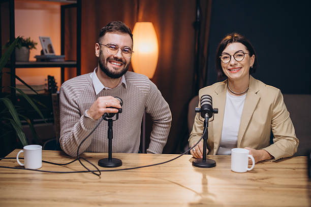 istock Two happy podcasters speaking into microphones while recording a new podcast episode in a professional studio 2209403087