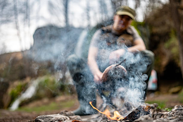 istock Person Cooking Sausages Over Open Fire in Outdoor Wilderness 2209406089