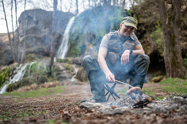 Man Enjoys Roasting Sausages by Campfire in Scenic Waterfall Setting