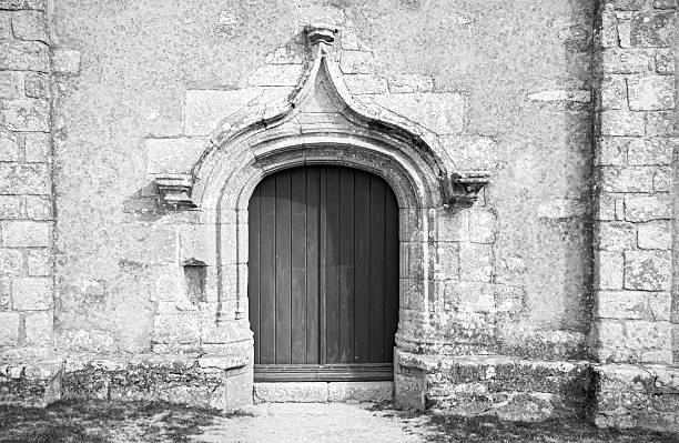 Close-up on old doors and staircase with plants and moss, with medieval architecture. This photo was taken at the Notre Dame d'Ambronay Abbey famous local monument in the French village of Ambronay, in the Ain department in the Auvergne-Rhone-Alpes region.