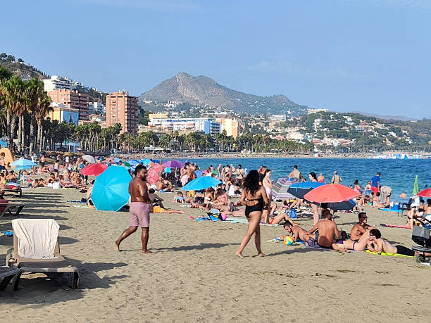 Lloret de Mare, Catalonia, Spain, 1972. A vacationer reads a newspaper on a beach in Spain.