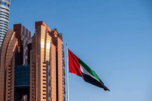 istock UAE  flag waving on blue sky,  High rise buildings background in Abu Dhabi 2209406773