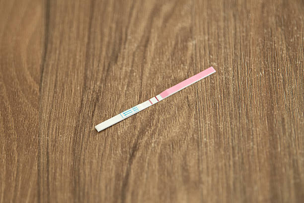istock A pregnancy test strip rests on a wooden surface, indicating two lines that suggest a positive result. The setting is well-lit, highlighting the simplicity of the scene 2209407343
