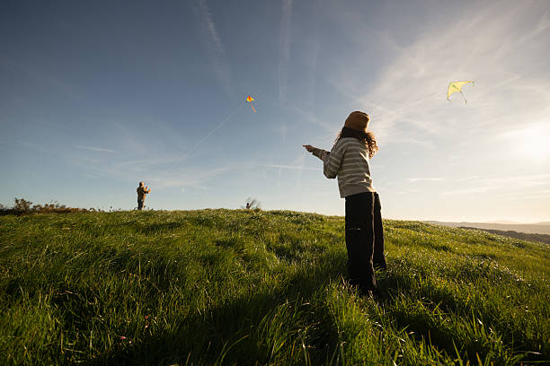Father and his two daughters are enjoying a sunny day flying kites on a grassy hilltop, creating a heartwarming scene of family bonding and outdoor fun