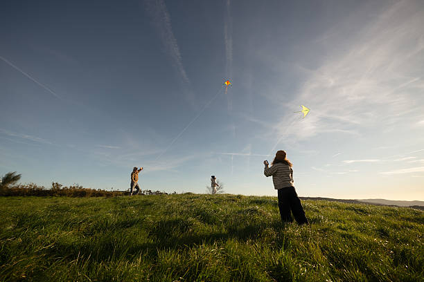 Father and his two daughters enjoying a sunny day in a vibrant meadow, flying colorful kites and creating joyful memories while bonding together in nature's beauty
