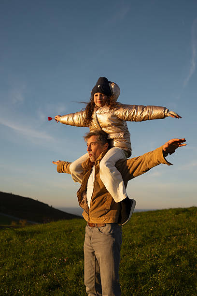 istock Father and daughter playing airplane on meadow at sunset 2209409739