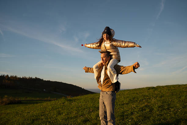 istock Father and daughter playing airplane in a meadow at sunset 2209409744