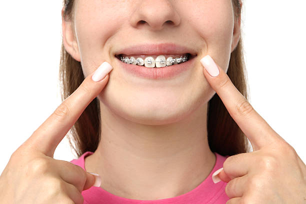 istock Girl pointing at her braces on white background, closeup 2209411326