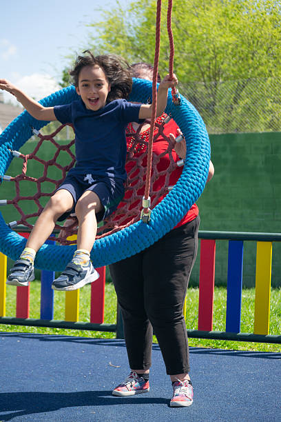 istock Mother pushing her cheerful son on a swing at the playground 2209411960