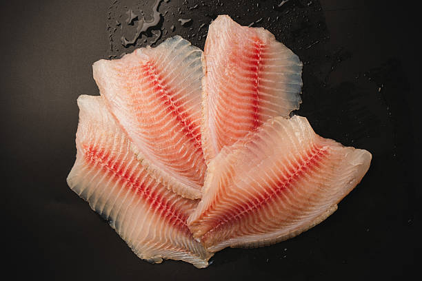 istock Fresh tilapia fillet on black background, top view. 2209412862