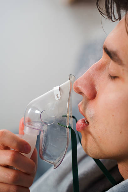 istock Using compressor nebulizer for disease treatment at home. Man inhaling through oxygen mask for cough treatment. 2209413094