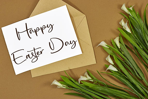 istock Easter lily white spring flower and paper card in envelope with text Happy Easter on brown background 2209413882