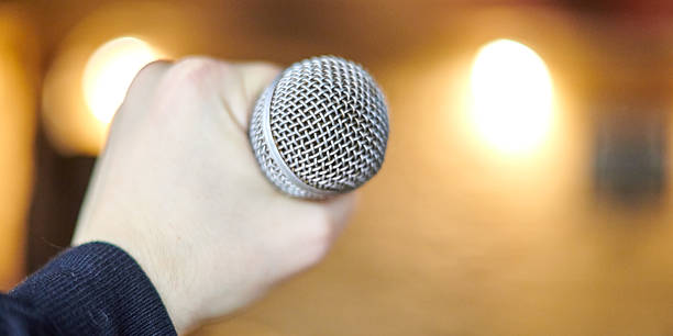 istock Close Up Of Hand Holding Microphone In Dramatic Lighting Setting For Performance 2209416176