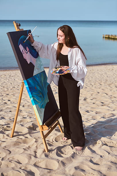 istock Young female painter creating art by seashore 2209416307
