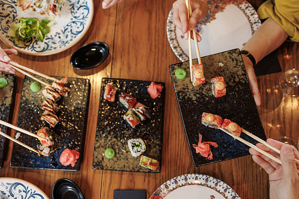 istock Group sharing sushi rolls at a wooden table in a social dining setting 2209419446