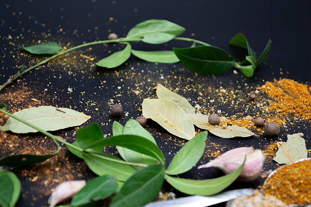 Aromatic Assortment of Spices and Herbs for Culinary Delights a variety of spices and herbs arranged on a dark, circular stone surface. Small bowls contain ingredients Various spices and herbs in bowl