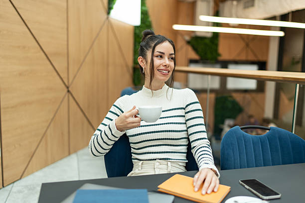 istock Smiling young woman using phone and enjoying in coffee 2209421902