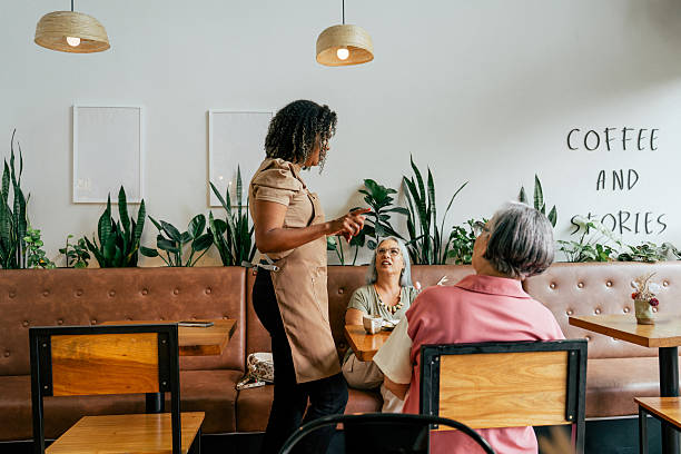 istock Coffee shop owner talking to customers 2209425804