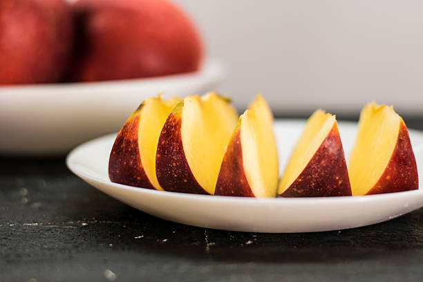 Still life stack of white ceramic plates with red apples, on white background