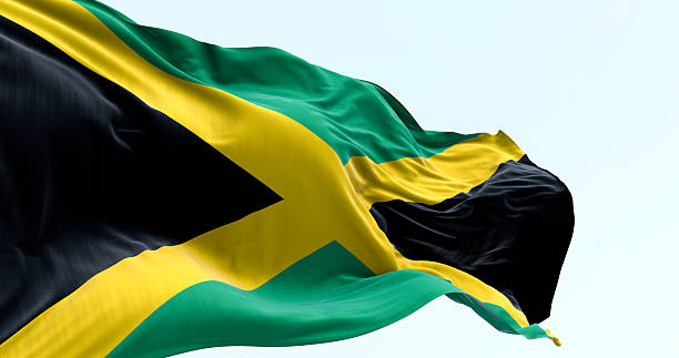 Jamaican flag with yellow saltire waving in wind on clear sky, 3D render