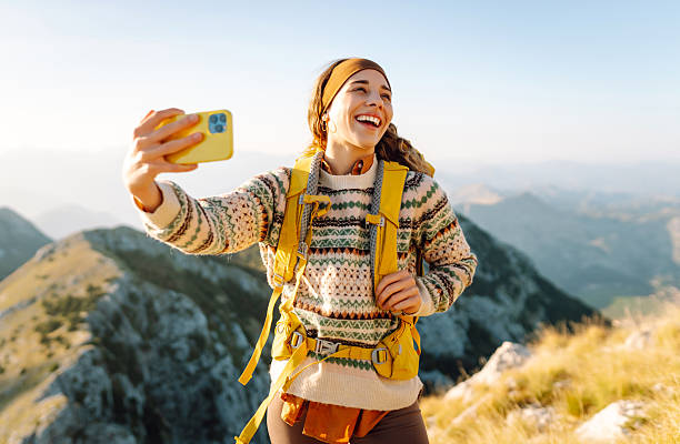 istock Hiker with bright hiking gear taking selfie on mountain. 2209427718