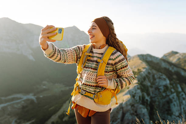istock Hiker with bright hiking gear taking selfie on mountain. 2209427723