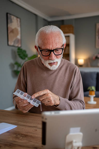 istock Senior man showing pill organizer during telehealth appointment 2209428444
