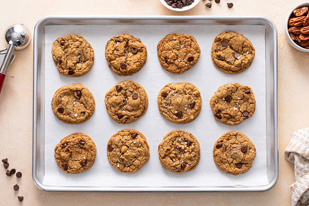 Chocolate chip cookies with pecan nuts, freshly baked cookies on a baking sheet lined with parchment