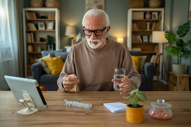 istock Senior man taking medication while following instructions on digital tablet at home 2209430381