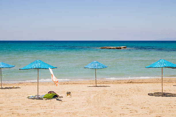 Close up taken of calm beach with blue color straw umbrellas with turquoise sea