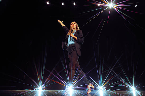 istock Entertainer with Microphone on Stage Speaking to Audience 2209449853