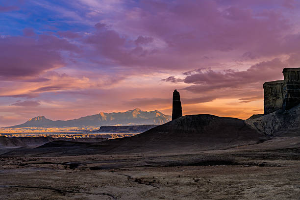Tall Mysterious Rock Spire Formation in the Desert - Scenic view of rock formation with the Henry Mountains as a backdrop captured in late afternoon sunset light.