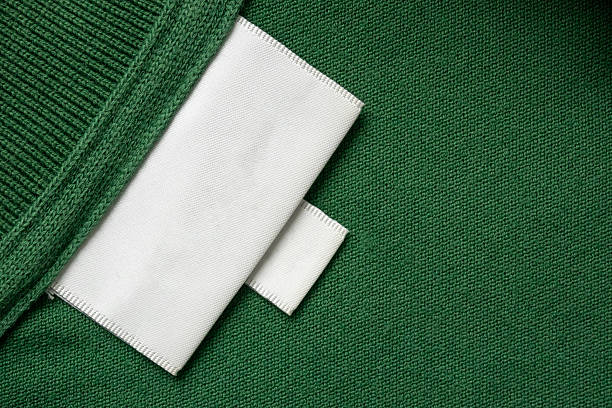 istock Blank white laundry care clothes label on green shirt fabric texture background 2209452745