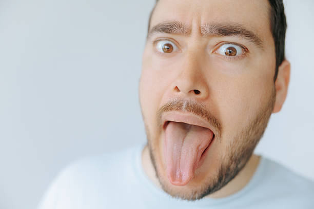 istock Man sticking out tongue with surprised expression in a light setting 2209457345