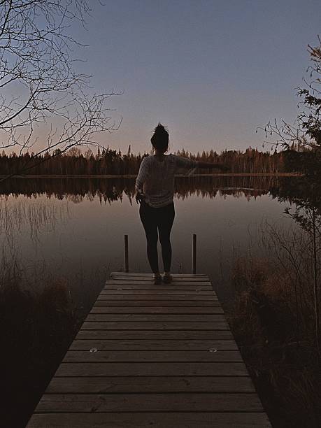 istock Woman Standing on Dock in Mindful Pose Overlooking Lake at Sunset. 2209457381
