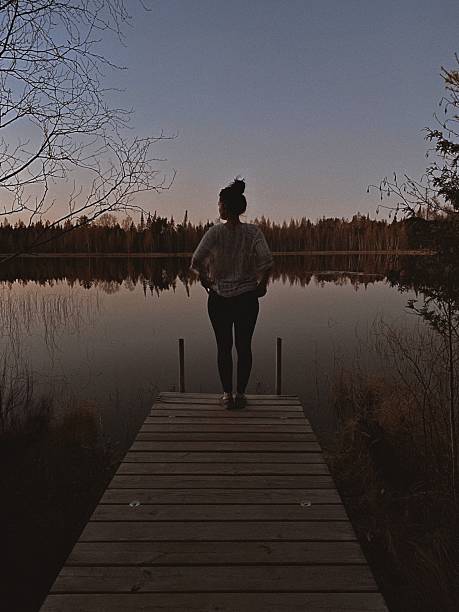 istock Woman Standing on Dock in Mindful Pose Overlooking Lake at Sunset. 2209457417