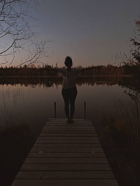 istock Woman Standing on Dock in Mindful Pose Overlooking Lake at Sunset. 2209457937