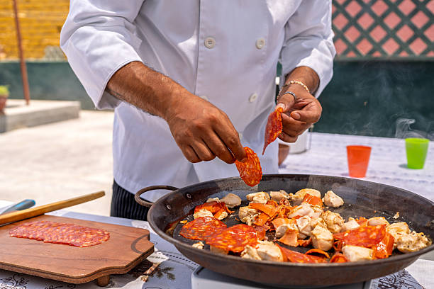 istock Chef adding chorizo to paella with chicken on a terrace 2209462353