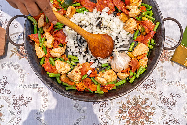 Chef skillfully stirs ingredients in a paella pan, creating a flavorful dish for a family gathering outdoors